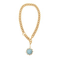 Gold chain necklace with a blue gemstone pendant on a white background