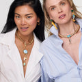 Two women wearing necklaces with various pendants on a plain background